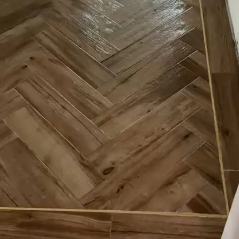 A close-up of warm wood-look herringbone tiling shared by Global Tiles & Bathrooms